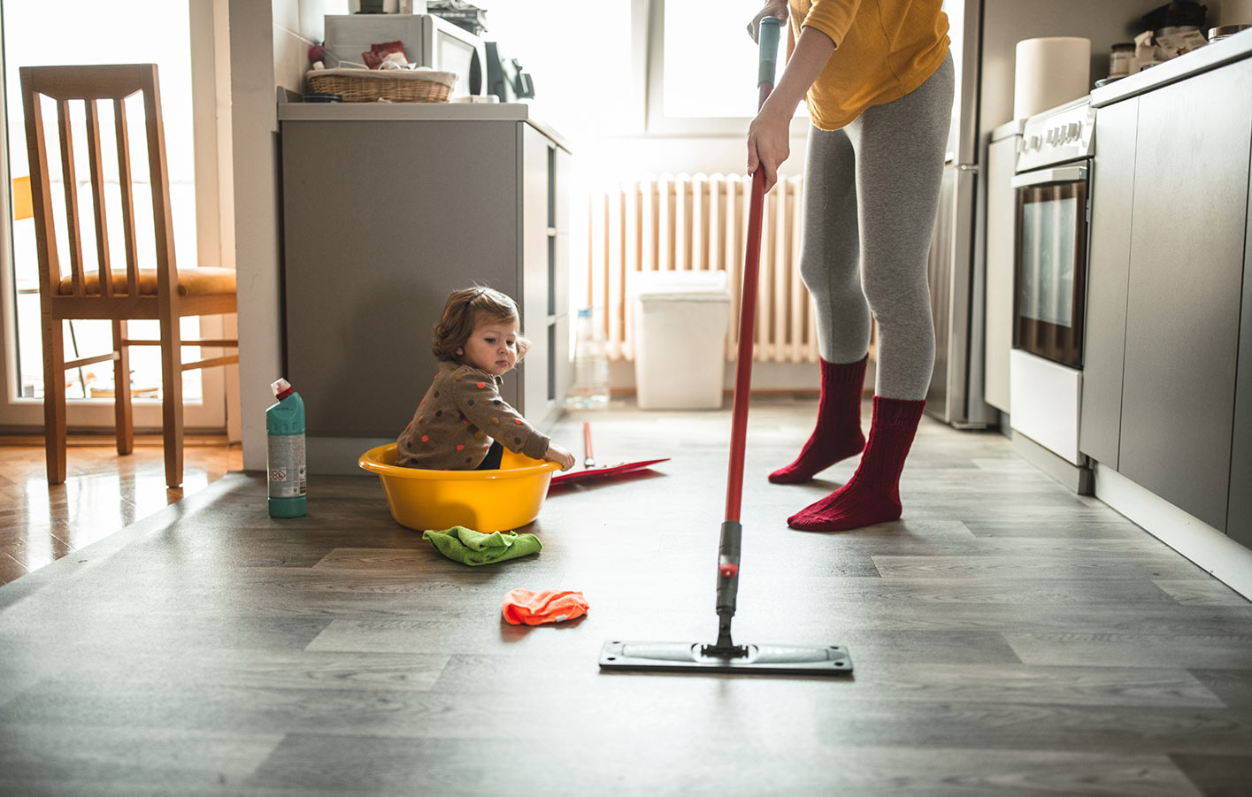 moderne offene Küche - Mutter wischt Bodenbelag - Kind sitzt daneben