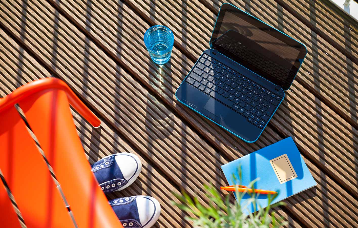 Laptop, Notizbuch, Wasser, Schuhe und ein Stuhl auf einem Terrassenausschnitt